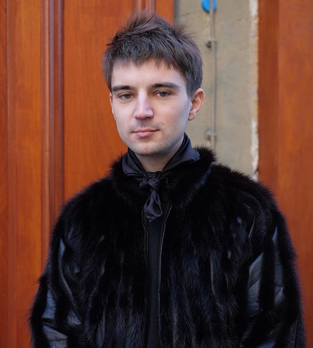 black silk scarf, black shirt and black fur jacket. definitely fashion weeking. not sure if it's a men's or women's fur but he owned it.